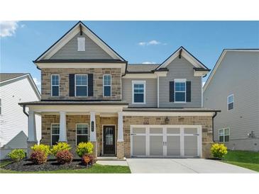 Charming two-story home boasts a stone and gray facade, complemented by black shutters and a well-manicured front yard at 1543 Dover Creek Ln, Lawrenceville, GA 30045