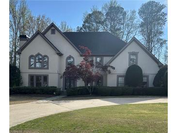 Charming home with manicured lawn, mature trees, and a traditional facade with beautiful windows at 9290 Prestwick Club Dr, Johns Creek, GA 30097