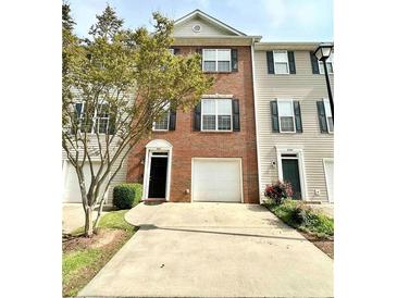 Charming townhome with a well-maintained brick facade, lush greenery, and a spacious driveway at 5401 Fox Creek Lane, Norcross, GA 30071