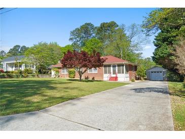 Charming brick home with a well-manicured lawn, a long driveway, and a detached garage at 566 Huff St, Lawrenceville, GA 30046