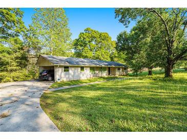 Charming single-story home with a well-manicured lawn, carport, and mature trees at 3150 Stonewall Tell Rd, Atlanta, GA 30349