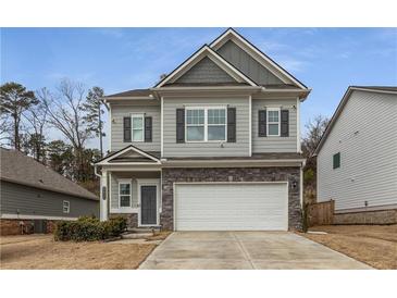 Charming two-story home with a gray exterior, stone accents, black shutters, and a two-car garage at 9032 Jim Purcell Dr, Covington, GA 30014