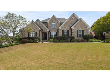 Inviting brick home featuring a manicured front lawn and mature landscaping, enhancing its curb appeal at 5604 Mccullers Ln, Loganville, GA 30052