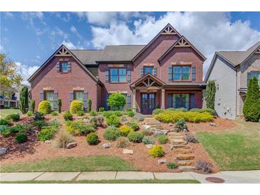 Stunning brick home featuring manicured landscaping, stone steps and charming architectural details on a sunny day at 2631 Moon Chase Lane, Buford, GA 30519