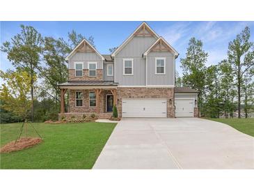 Charming two-story home featuring a brick and gray exterior, covered porch, and three-car garage at 7515 Woolf Way, Cumming, GA 30028