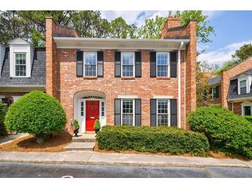 Charming brick townhome featuring a red front door, black shutters, and manicured landscaping at 12 Valley Forge Nw Pl # 215, Atlanta, GA 30318