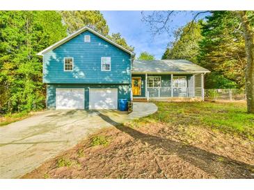 Charming home featuring a two-car garage and covered porch, surrounded by mature trees at 622 Jockey Ln, Auburn, GA 30011