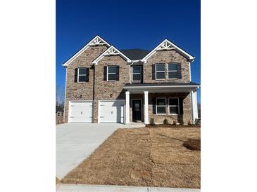 Two-story brick home featuring a two-car garage and classic architectural design with a clean blue sky at 669 Egrets Lot 56 Lndg, Covington, GA 30014