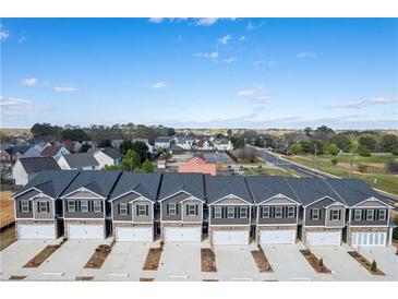 New townhomes with brick accents, white garage doors, and landscaping offer modern curb appeal at 11561 Kimberly Way # 23, Hampton, GA 30228