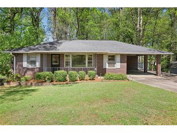 Charming brick home features a well-maintained lawn, mature trees, and a convenient carport at 1316 Sanders Dr, Morrow, GA 30260