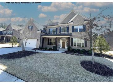 Beautiful two-story brick home featuring a manicured front lawn, black shutters, and a two-car garage at 13015 Fox Rd, Alpharetta, GA 30005