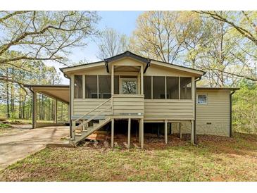 Inviting exterior showcasing a charming tan home with a screened-in porch and convenient carport at 5026 Daniel Mill Rd, Winston, GA 30187