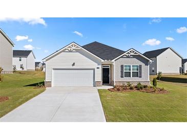 Charming single-story home featuring a two-car garage, manicured lawn, and a welcoming entrance at 604 Lobelia Way, Locust Grove, GA 30248