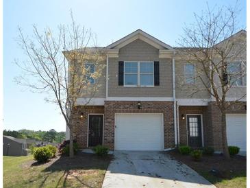 Charming townhome featuring a one-car garage and brick and beige siding with a well-maintained front yard at 5829 Taka Ln, Lithonia, GA 30038
