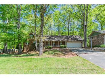 Charming one story brick home featuring a two car garage, covered front porch, and mature trees at 2352 Rockwood Way, Stone Mountain, GA 30087