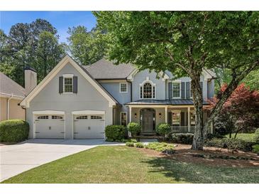 Charming two-story home with a well-manicured lawn, covered porch, and attached two-car garage at 12370 Preserve Ln, Johns Creek, GA 30005