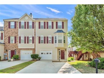Inviting townhome with red shutters, a two car garage, and well-maintained landscaping at 745 Abbotts Mill Ct, Johns Creek, GA 30097