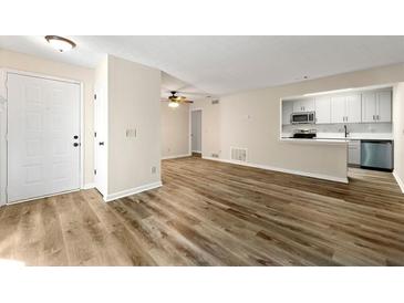 Bright living room featuring hardwood floors and an open layout to kitchen and dining area at 1371 Branch Dr, Tucker, GA 30084