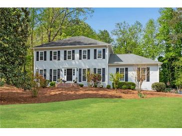 Charming two-story home with a well-manicured lawn and a classic facade with black shutters at 1953 Windcrest Sw Dr, Lilburn, GA 30047