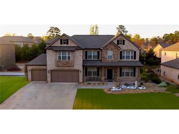 Beautiful two-story home featuring a well-manicured lawn, stone accents, and a two-car garage at 552 Warrenton Run Dr, Sugar Hill, GA 30518