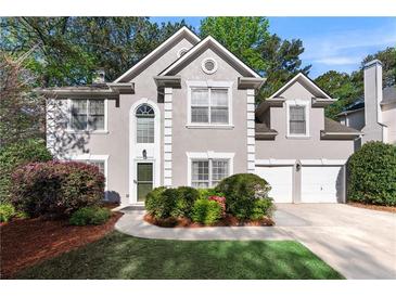 Charming stucco two-story home with a well-manicured lawn and two-car garage at 1035 Bridle Path Dr, Lawrenceville, GA 30045
