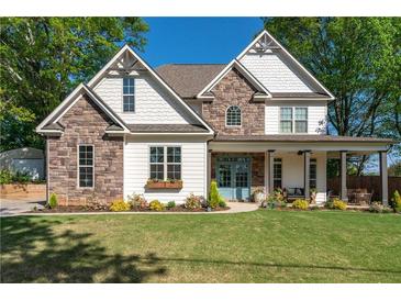 Charming two-story home featuring stone accents, white siding, and a welcoming front porch with craftsman-style details at 235 South St, Buford, GA 30518