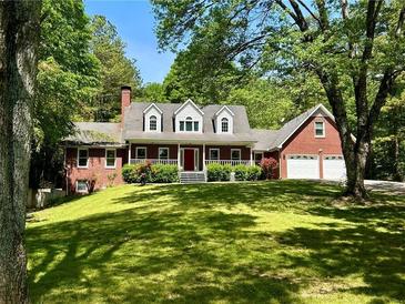 Charming brick home with a red door, dormer windows, two-car garage and a well-manicured lawn at 999 Grassdale Rd, Cartersville, GA 30121
