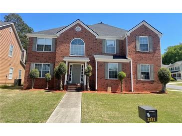 Charming two-story brick home with a well-manicured lawn, complemented by trimmed bushes at 2347 Fawn Hollow Ct, Duluth, GA 30096