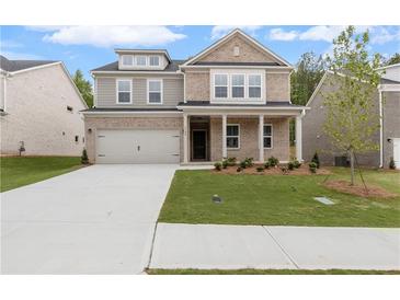 Inviting two-story brick home featuring a well-manicured lawn and an attached two-car garage at 6100 Marigold Way, Atlanta, GA 30349