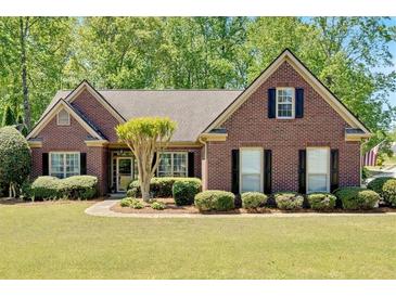 Charming brick home with manicured lawn, complemented by mature trees and classic black shutters at 4309 Milford Pl, Hoschton, GA 30548