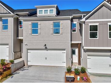 New townhome with grey brick, white garage door, and manicured landscaping at 1227 Fern Ridge Ct # 17, Norcross, GA 30093
