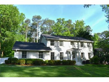 Charming white brick two-story home with dark roof, shuttered windows and well-manicured front lawn at 3562 Sunderland Ne Cir, Atlanta, GA 30319