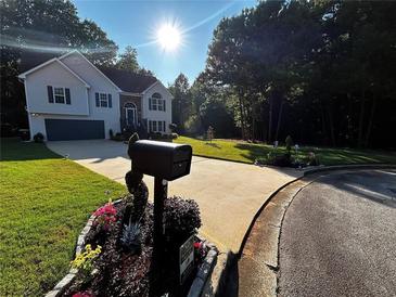 Charming two-story home featuring manicured front lawn, inviting curb appeal, and attached two car garage at 3927 Villager Way, Rex, GA 30273