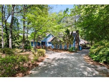 Charming blue house with mature trees, a driveway, and a brick chimney at 1326 Janmar Rd, Snellville, GA 30078