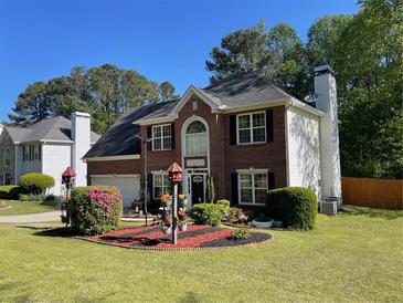 Charming two-story brick home featuring manicured lawn and a decorative flower garden in the front yard at 6010 Silver Lace Nw Ln, Acworth, GA 30101