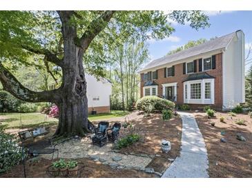 Charming brick home featuring lush landscaping and a welcoming walkway to the front door at 510 Birch Ridge Ct, Roswell, GA 30076