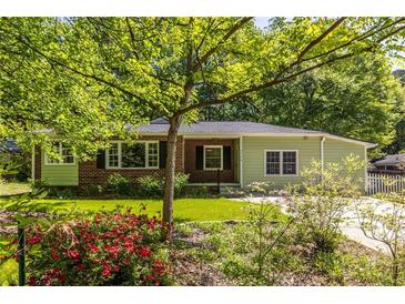 Charming home featuring a landscaped front yard with beautiful flowers and a classic brick and siding exterior at 1740 Fairbanks Sw St, Atlanta, GA 30310
