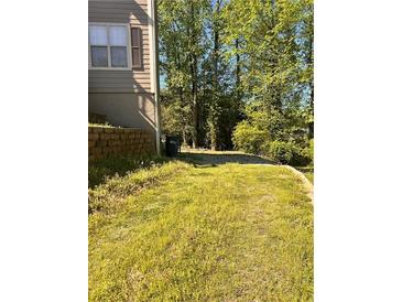 An expansive backyard with mature trees and an overgrown lawn at 7027 Grinder Drive, Austell, GA 30168