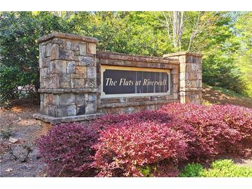 Stone community sign for The Flats at Riverwalk, surrounded by vibrant landscaping at 1910 Cedar Glenn Way # 4104, Atlanta, GA 30339