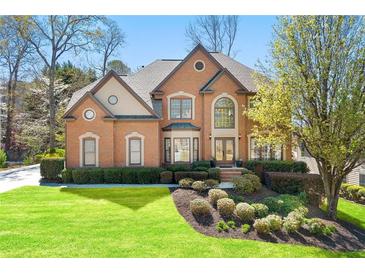 Charming brick home featuring a lush green lawn and manicured landscaping at 317 Vista Lake Dr, Suwanee, GA 30024