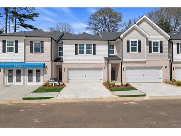 Charming townhome featuring a brick and siding facade, two-car garage, and well-manicured landscaping at 413 Brooch Way, Stockbridge, GA 30281
