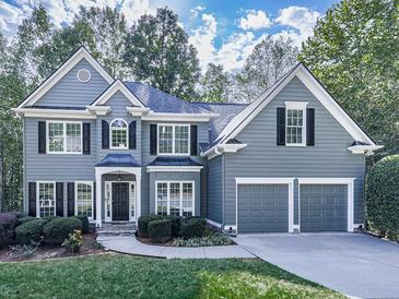 Charming two-story home with gray siding, black shutters, manicured landscaping, and an attached two-car garage at 907 Fox Croft Pl, Canton, GA 30114
