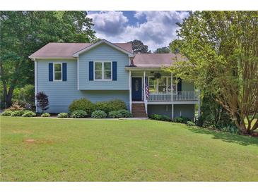 Charming light blue home with a covered porch, well-manicured lawn, and mature trees at 2675 Dacula Ridge Dr, Dacula, GA 30019