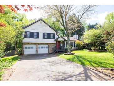 Charming two-story home featuring a stone facade, red door, two-car garage and a well-manicured lawn and mature trees at 1763 Hearthstone Cir, Lawrenceville, GA 30043