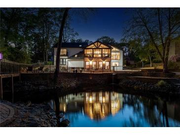 Stunning exterior view of a modern home reflected in a tranquil pond at night at 2750 Interlaken Dr, Marietta, GA 30062