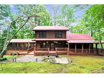 Charming log home with a red metal roof, spacious porch and screened in porch surrounded by mature trees at 800 Knox Ln, Canton, GA 30114