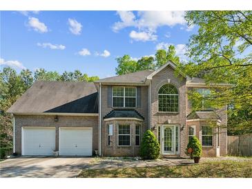 Charming two-story brick home with a well-manicured lawn, two-car garage, and beautiful, arched entryway at 2130 Boulder Gate Dr, Ellenwood, GA 30294