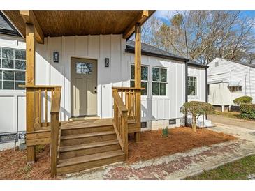 Charming front entrance featuring a wooden porch, white siding and modern light fixtures at 1111 Edgefield Sw Dr, Atlanta, GA 30310