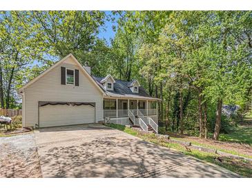 Charming two-story home with a front porch, attached garage, and mature trees on a sunny day at 365 Falling Timber Ct, Stockbridge, GA 30281