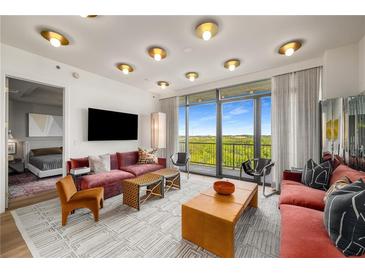 Bright living room with hardwood floors, contemporary furniture, and floor-to-ceiling windows with scenic views at 2233 Peachtree Ne Rd # 1207, Atlanta, GA 30309